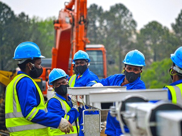 Several construction workers are assembling the substructure on which the solar panels will later be mounted.