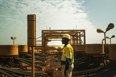 An employee stands in front of a large industrial facility that belongs to a mine.